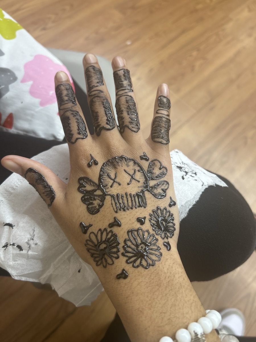 Detailed freestyle henna design across the hand and fingers